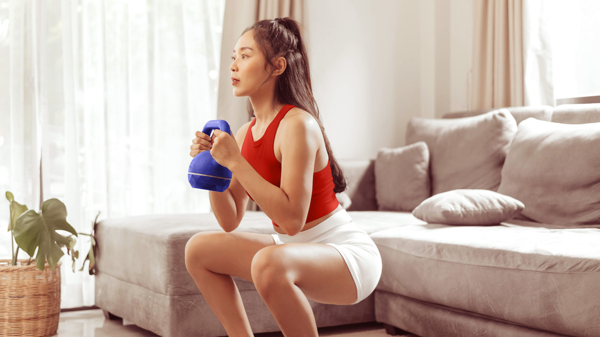 A beautiful asian woman doing the squats with a kettlebell